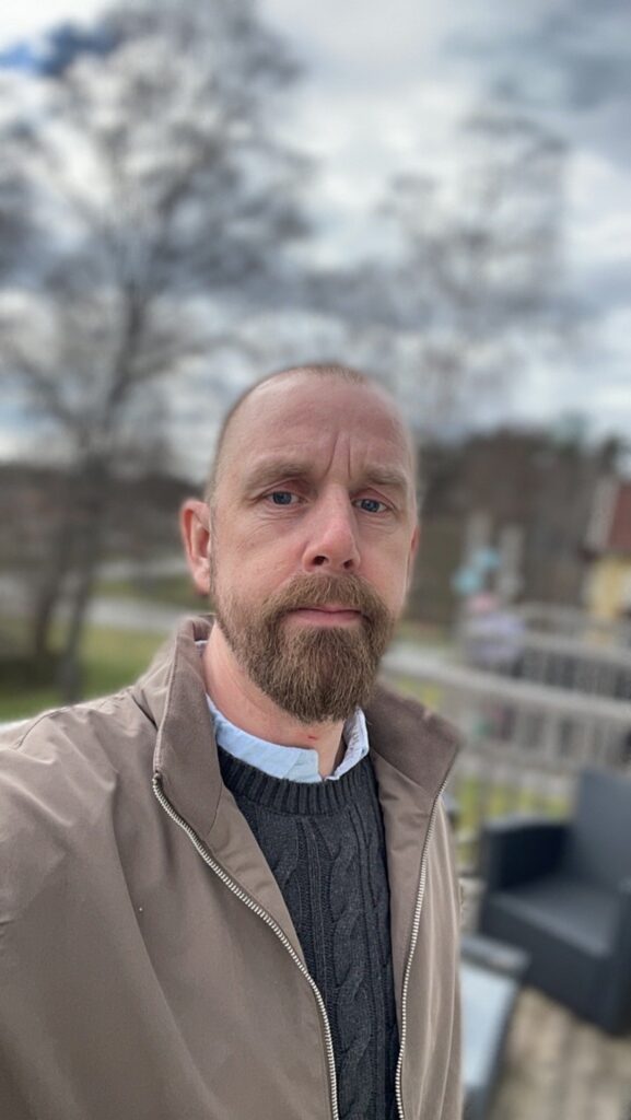 Porträtt av en man som står utomhus, med fokus och lugn i blicken.