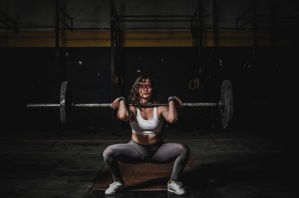 Gemenskap i träning – Kvinna som utför front squats med stång för att bygga styrka hos Stark Tillsammans